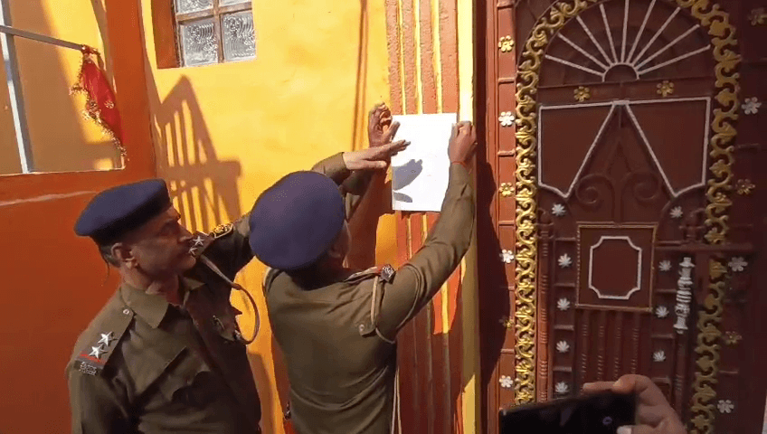 फरार अभियुक्त के घर चस्पाया गया न्यायालय का इश्तेहार